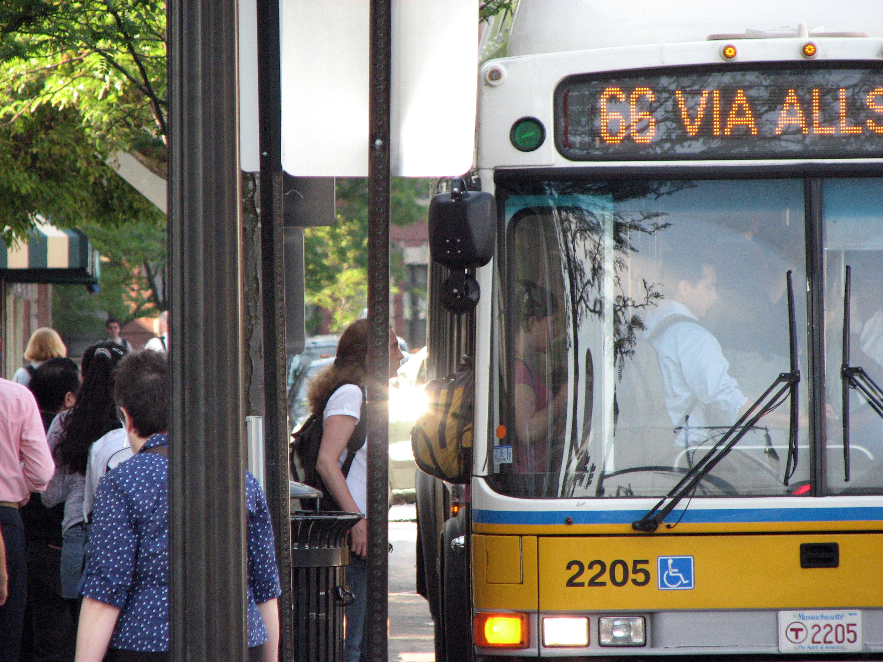 Photo of an MBTA bus picking up passengers at a bus stop.